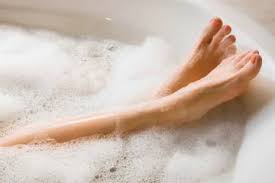 This picture shows the legs of a lady in the bath, surrounded by bubbles