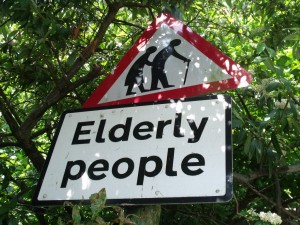 the highway code sign for the elderly with an man and woman in black walking with a stick in a red triangle