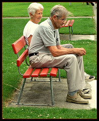 elderly couple sat on a park bench