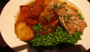 roast dinner,peas,potatoes and roast meat on a white plate