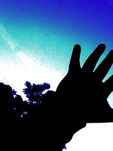 a black silhouette of a hand against a blue sky