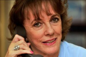 this image shows the late Dame Esther Ranzen holding an old fashioned telephone to her ear