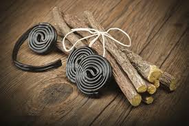 Does Liquorice relieve constipation? This image shows two coils of liquorice sweets and a bundle of pure liquorice root tied with a string bow. The background is a dark natural wood table top.