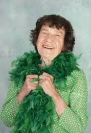 this image shows an older woman wearing a green blouse and feather boa. She is Lynne Ruth Miller and part of the "Old Folks Telling Jokes" at the recent Edinburgh festival.