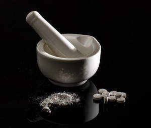 this image shows a pestle and mortar and some white tablets.