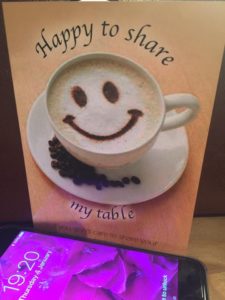 this image shows a mobile phone and a card that says "Happy to Share my table"