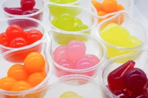 How good are Jelly Drops? This image shows a selection of small clear tear-drop shaped pots filled with coloured water filled sweets.