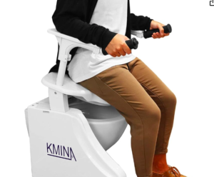 This image shows a raised toilet seat. This one is electric. In the picture it is being demonstrated by a person wearing brown trousers and shoes and a white top. They are also wearing a black cardigan.