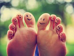 Washing your feet when you can't reach them. This image shows the soles of two feet. Each toe has a smiley face drawn on with pen. There is a mottled green background 