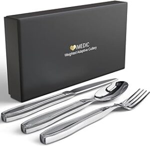Stylish cutlery with shaky hands. This image shows a stylish knife, fork and spoon set in stainless steel. The cutlery is arranged on a white surface and there is a black cardboard gift box behind them.