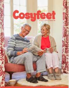 New Cosyfeet catalogue out now. This image shows the front cover of the new Cosyfeet footwear company catalogue. The cover has an older couple sat down on a dark peach two-seater sofa. They are browsing the catalogue and the woman has glanced up at her partner. There are peach and white patterned curtains to both edges of the couple which work as a frame for it.