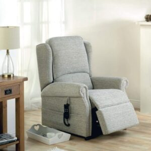 Health Benefits of Rise and Recline chairs. Image shows an grey armchair with the footplate slightly raised. There is a table to the side with a lamp on it