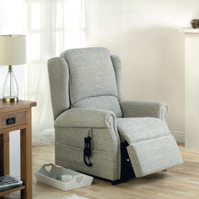Health Benefits of Rise and Recline chairs. Image shows an grey armchair with the footplate slightly raised. There is a table to the side with a lamp on it