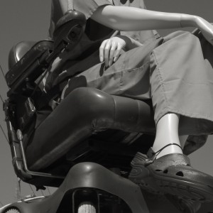 black and white picture of a dummy/model sat on a mobility scooter