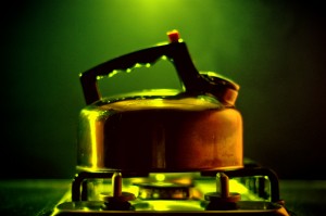 copper kettle on a gas stove with a green background