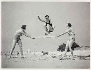 a black and white photo of 2 women and a man exercising on a beach