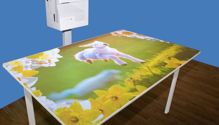 This shows an OM interactive Mobile projection system projecting a picture of a lamb onto a table top