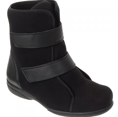 This article is called "Footwear For People Who Have Had A Stroke". This image shows an ankle boot that is black. It has a flat rubber sole and a slightly elevated heel. The boot is mid calf height and has two velcro straps to fasten.