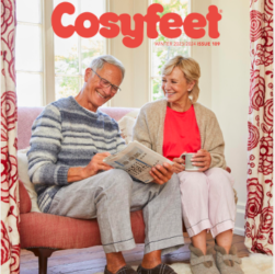 New Cosyfeet catalogue out now. This image shows the front cover of the new Cosyfeet footwear company catalogue. The cover has an older couple sat down on a dark peach two-seater sofa. They are browsing the catalogue and the woman has glanced up at her partner. There are peach and white patterned curtains to both edges of the couple which work as a frame for it.